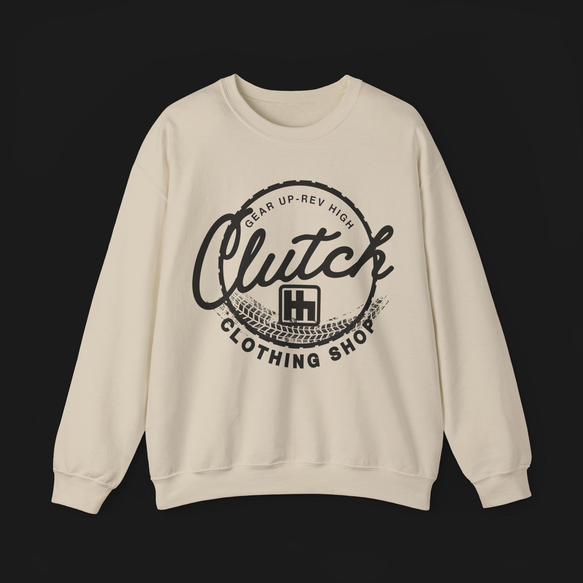 Front of Clutch Crewneck Automotive Sweater – Beige unisex sweater featuring a bold 'Clutch Clothing Shop' design with a tire tread circle and stylized text. Perfect for car enthusiasts and casual wear.
