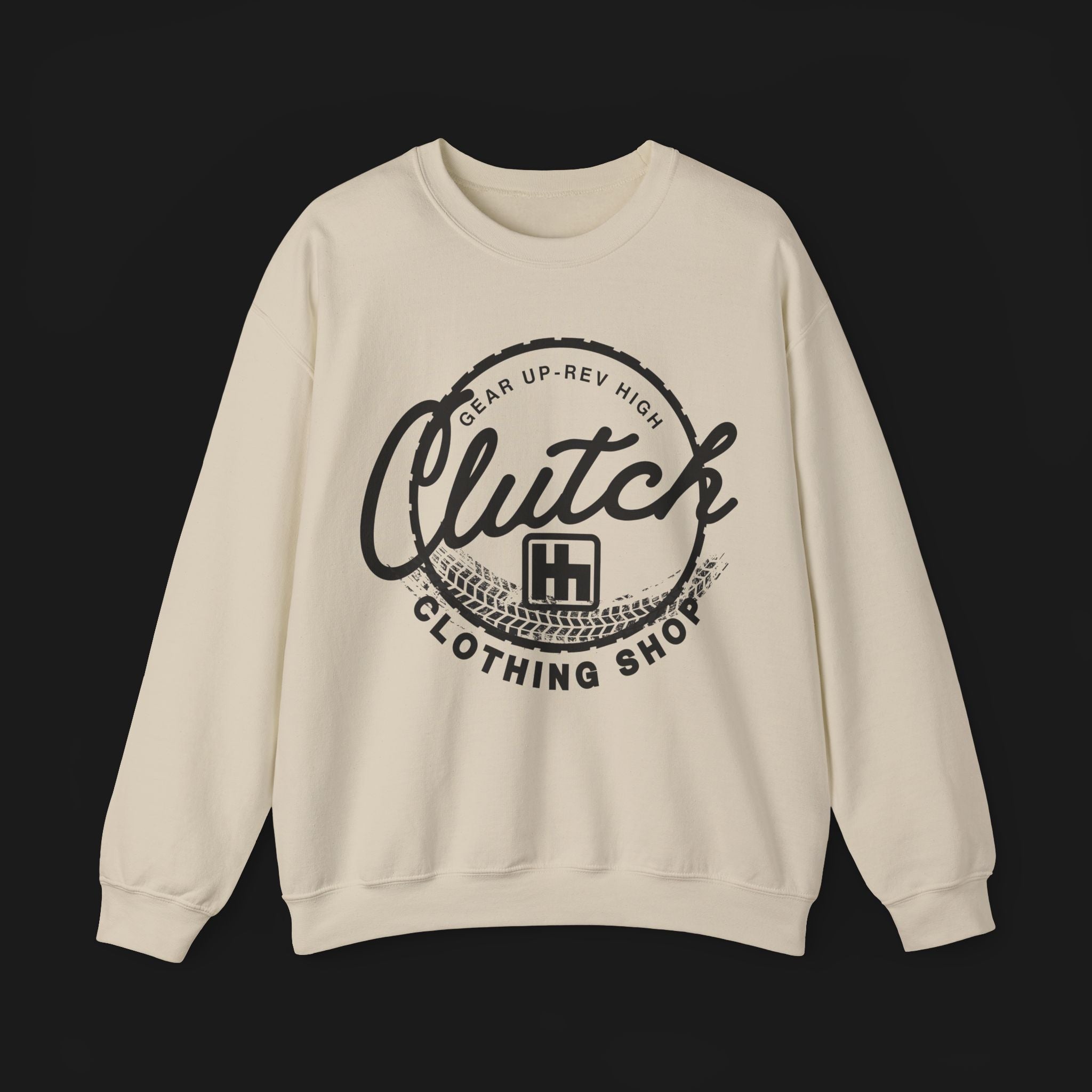 Front of Clutch Crewneck Automotive Sweater – Beige unisex sweater featuring a bold 'Clutch Clothing Shop' design with a tire tread circle and stylized text. Perfect for car enthusiasts and casual wear.
