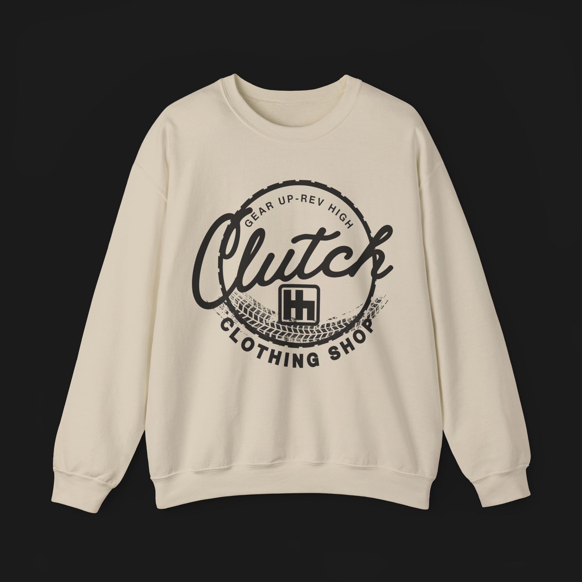 Front of Clutch Crewneck Automotive Sweater – Beige unisex sweater featuring a bold 'Clutch Clothing Shop' design with a tire tread circle and stylized text. Perfect for car enthusiasts and casual wear.