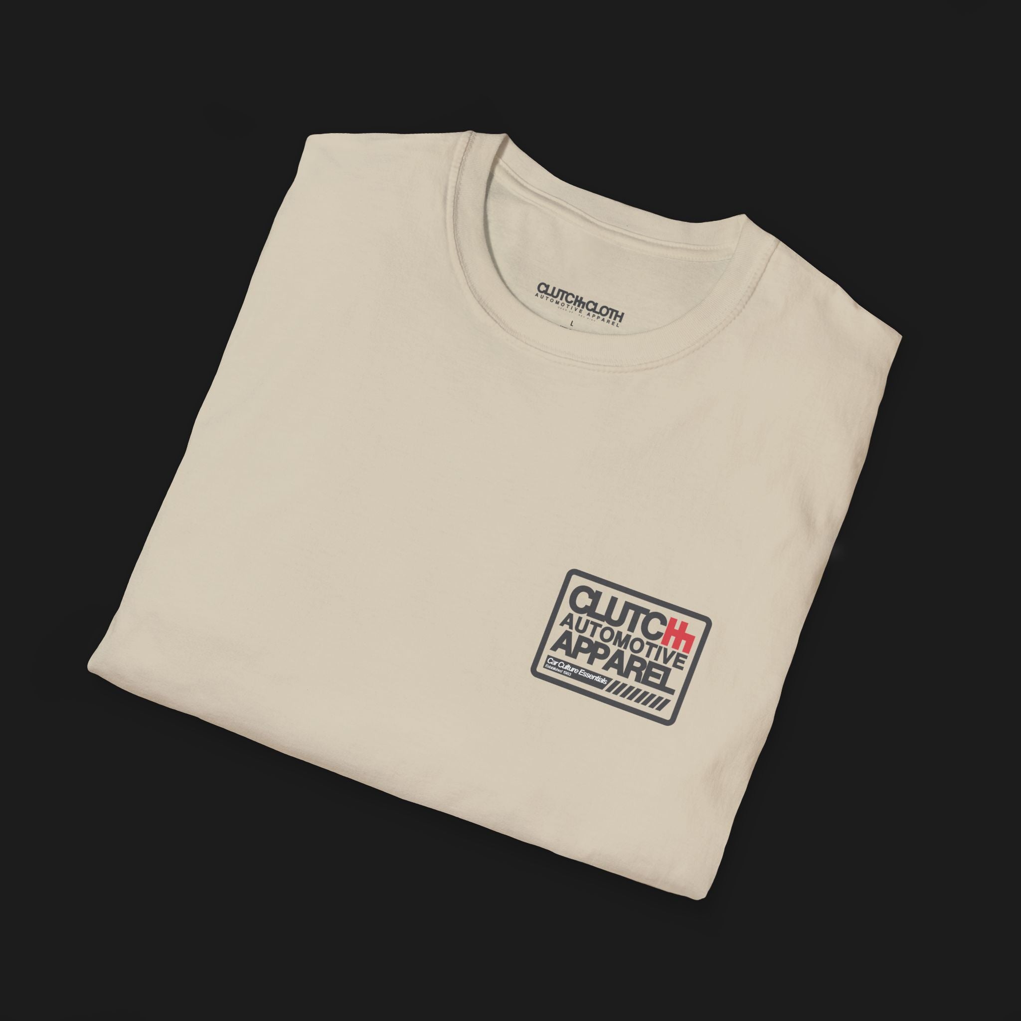 Folded Clutch Classic Unlock The Garage Automotive Graphic T-Shirt – Sand tee featuring a small "Clutch Automotive Apparel" chest design. Perfect gift for car lovers and gearheads.