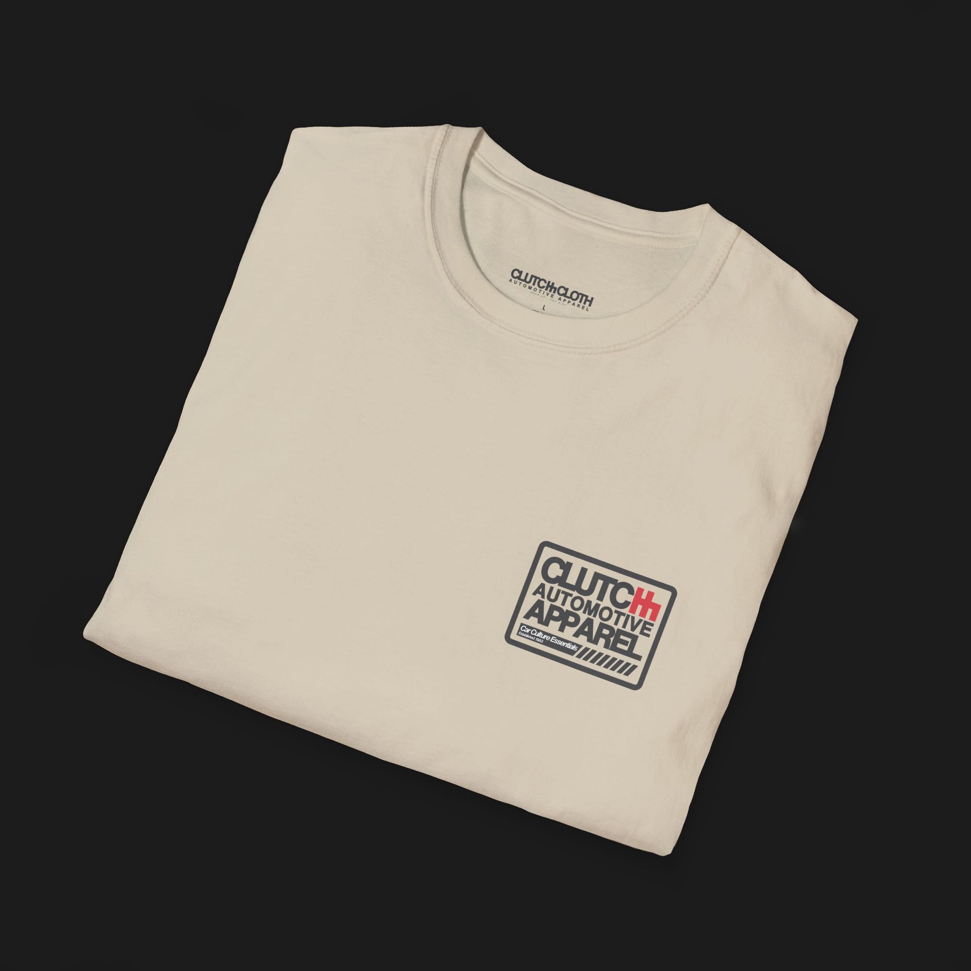 Folded Clutch Classic Unlock The Garage Automotive Graphic T-Shirt – Sand tee featuring a small "Clutch Automotive Apparel" chest design. Perfect gift for car lovers and gearheads.