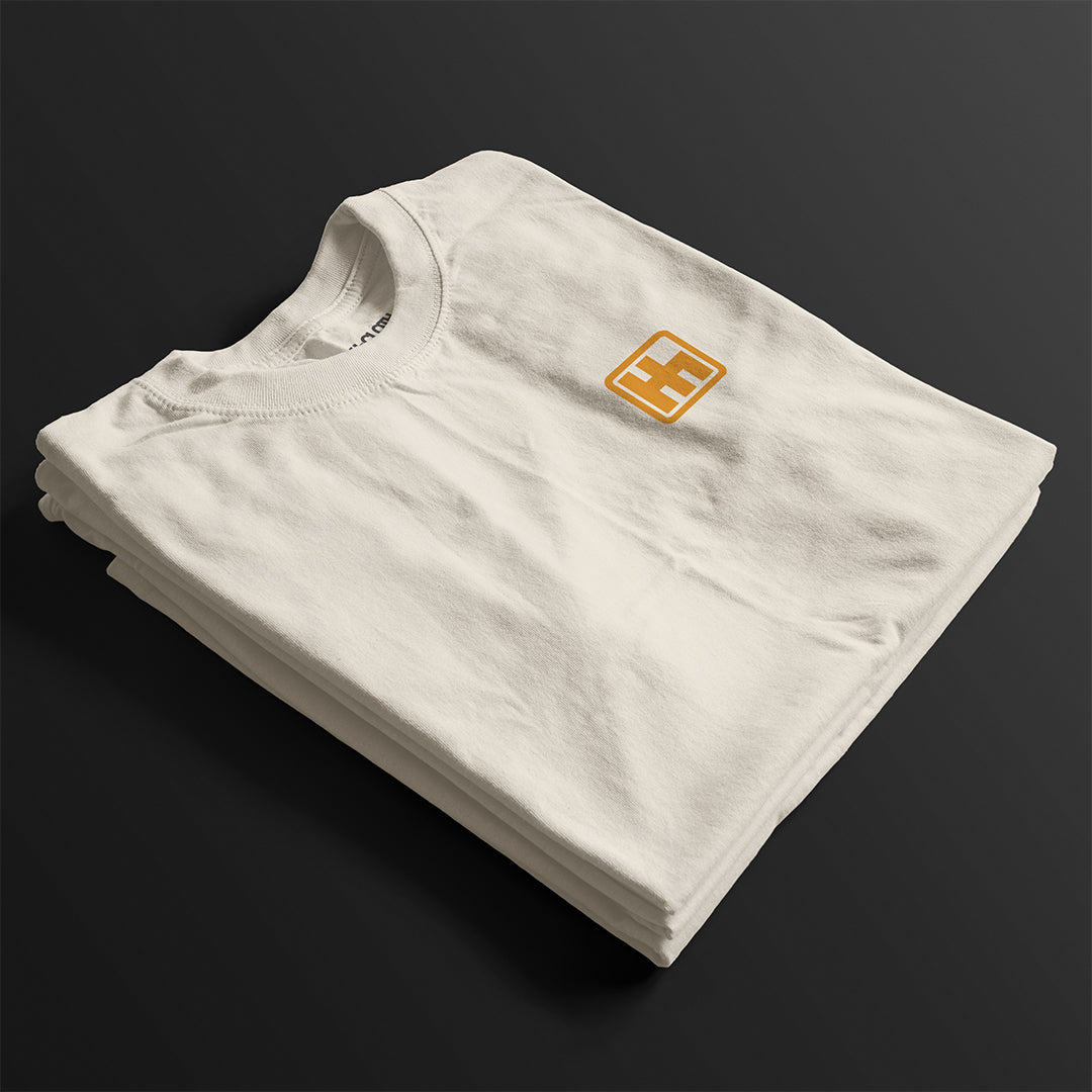 Folded Astonishingly Overkill Automotive Graphic T-Shirt – Beige tee featuring a bold Audi Quattro rally car design with a yellow overlay and "Astonishingly Overkill" text. Perfect gift for rally fans and car enthusiasts.
