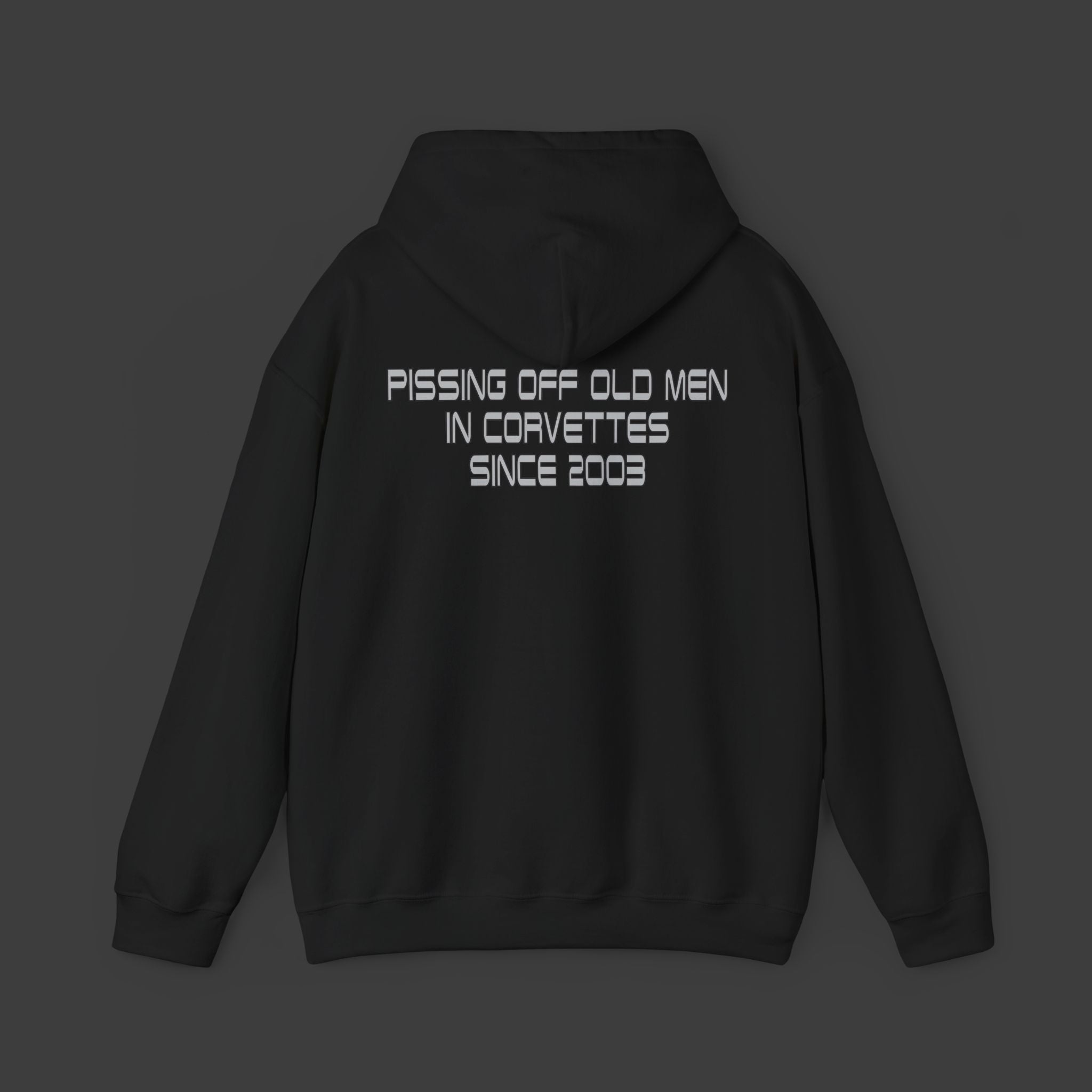 Black hoodie with text on the back on a dark background Pissing off old men in corvettes since 2003