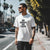 Man wearing No Dragy No Care Automotive Graphic T-Shirt – White tee with bold "No Dragy No Care" text design in black. Ideal gift for car culture fans and automotive enthusiasts.