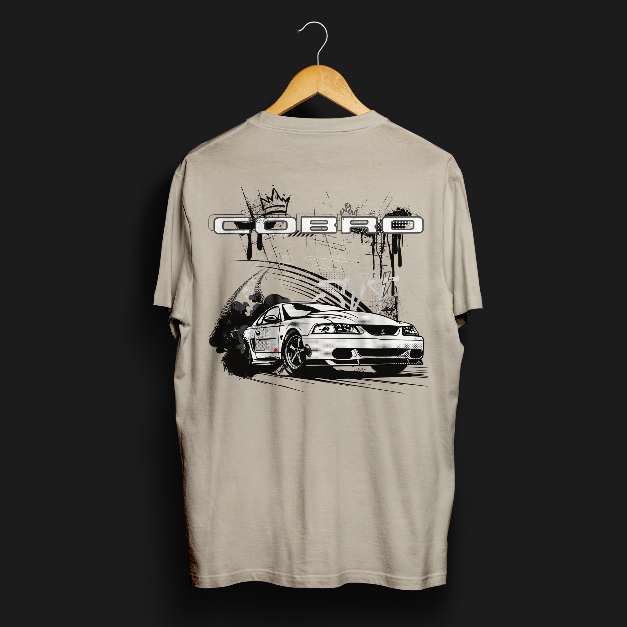 Back angle of Cobro x Clutch Automotive Graphic T-Shirt – Sand tee featuring a detailed white Mustang Cobra design with graffiti-style background and "Cobro" text. Perfect gift for Mustang fans and car enthusiasts.