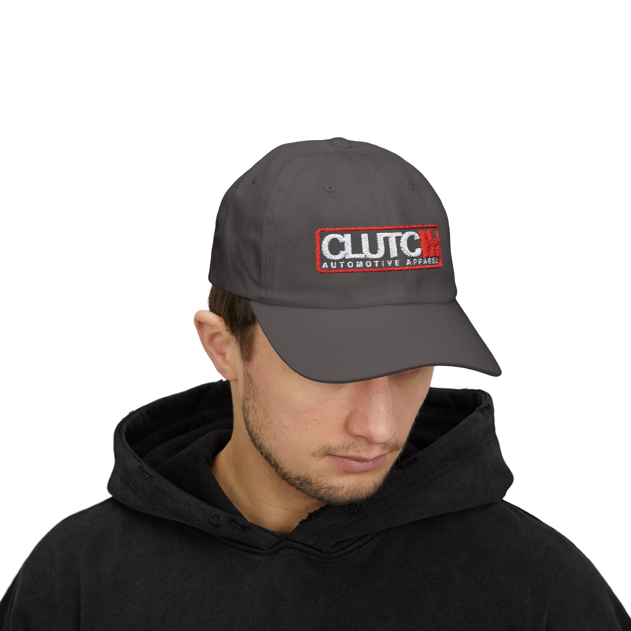 Man wearing Clutch Automotive Apparel Embroidered Dad Cap – Grey unisex dad cap featuring the "CLUTCH" logo with red and black embroidery. Made from high-quality fabric, offering a comfortable and adjustable fit. Perfect for car lovers and automotive enthusiasts.