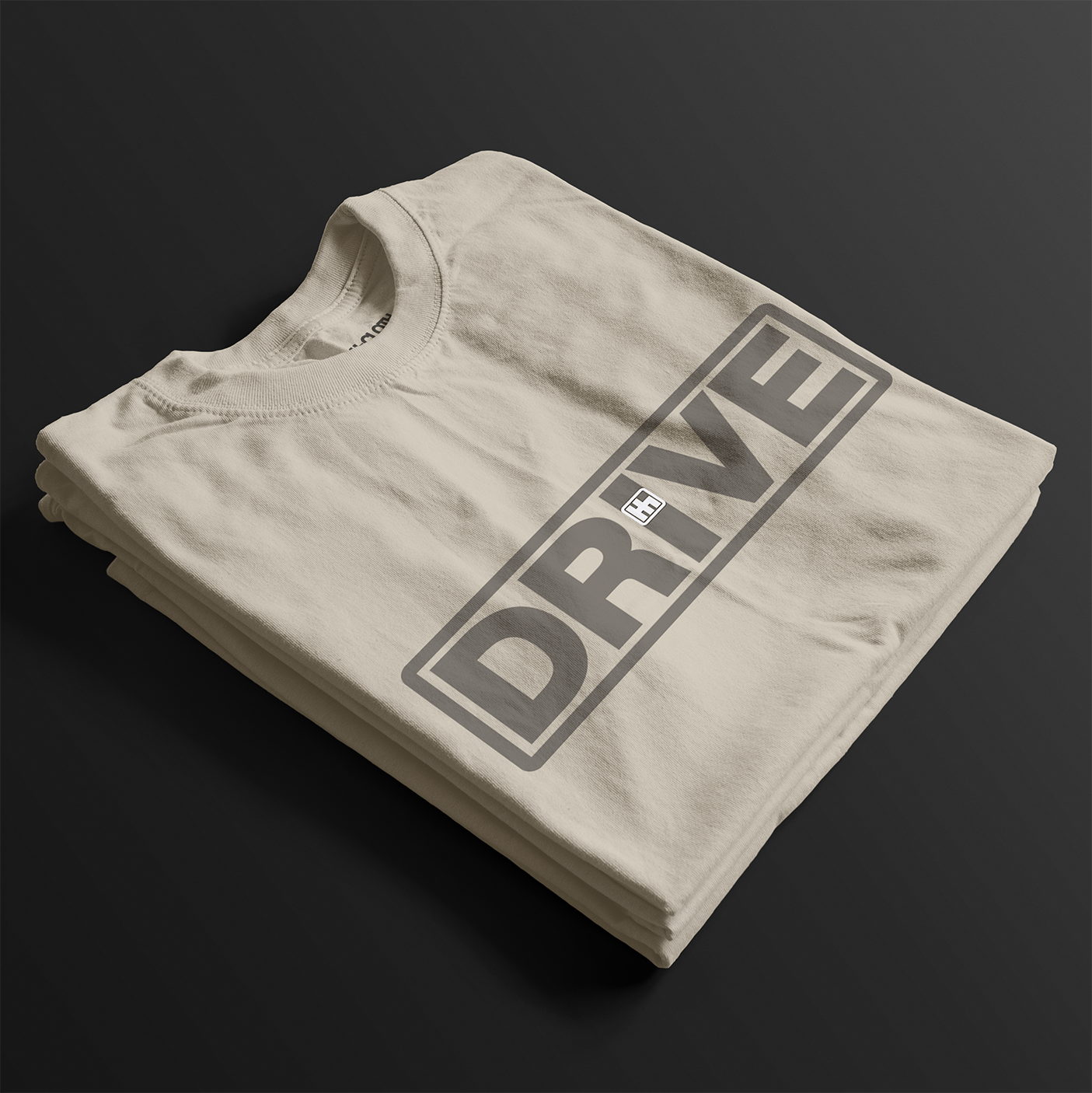 Folded Drive Automotive Graphic T-Shirt – Sand tee featuring bold "DRIVE" text with gear-inspired detailing. Perfect gift for car enthusiasts and racing fans.