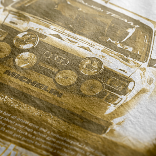 Back Design of Astonishingly Overkill Automotive Graphic T-Shirt – Beige tee featuring a bold Audi Quattro rally car design with a yellow overlay and "Astonishingly Overkill" text. Perfect gift for rally fans and car enthusiasts.